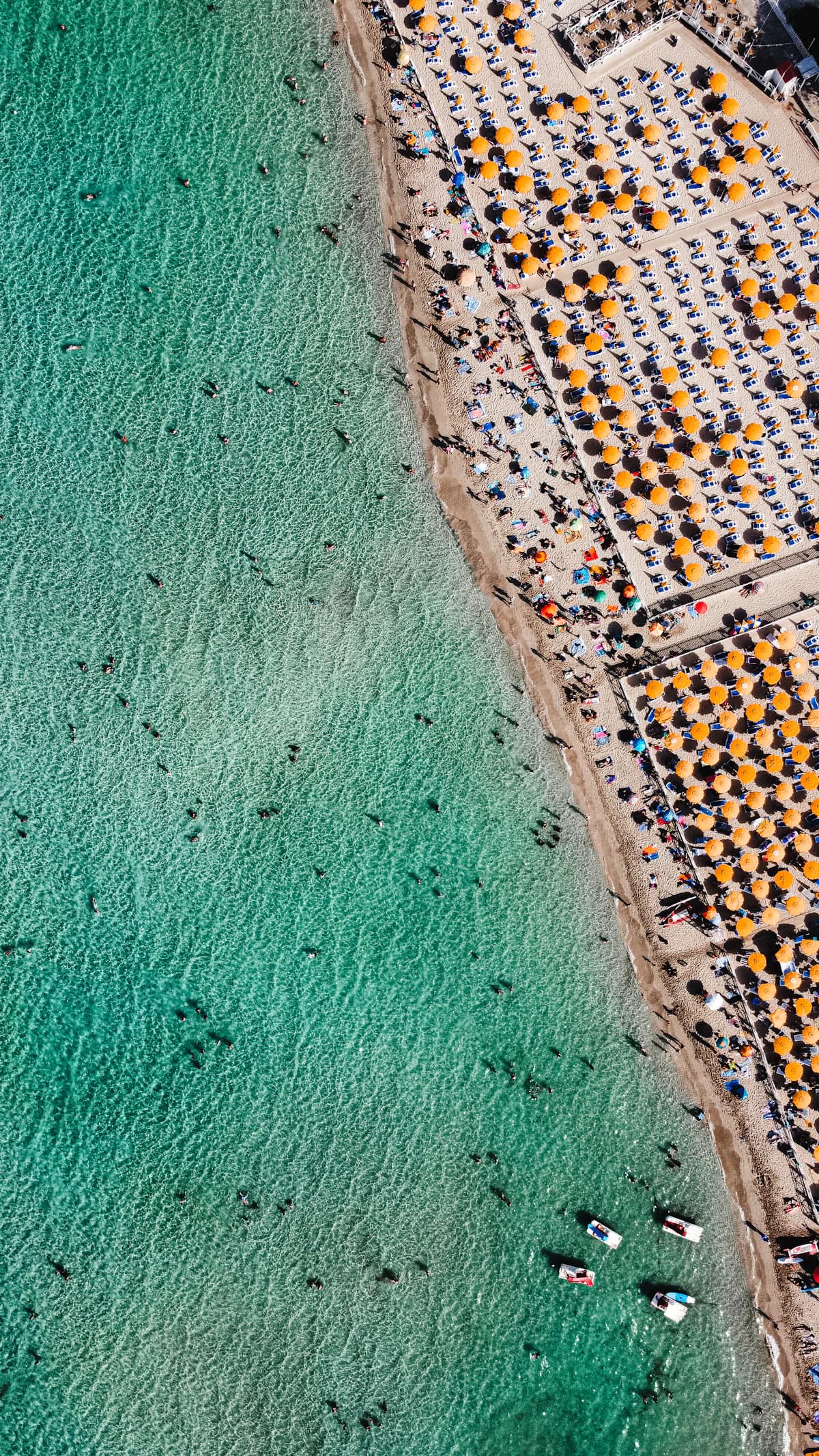 Aerial view of turquoise water and orange beach umbrellas at Mondello