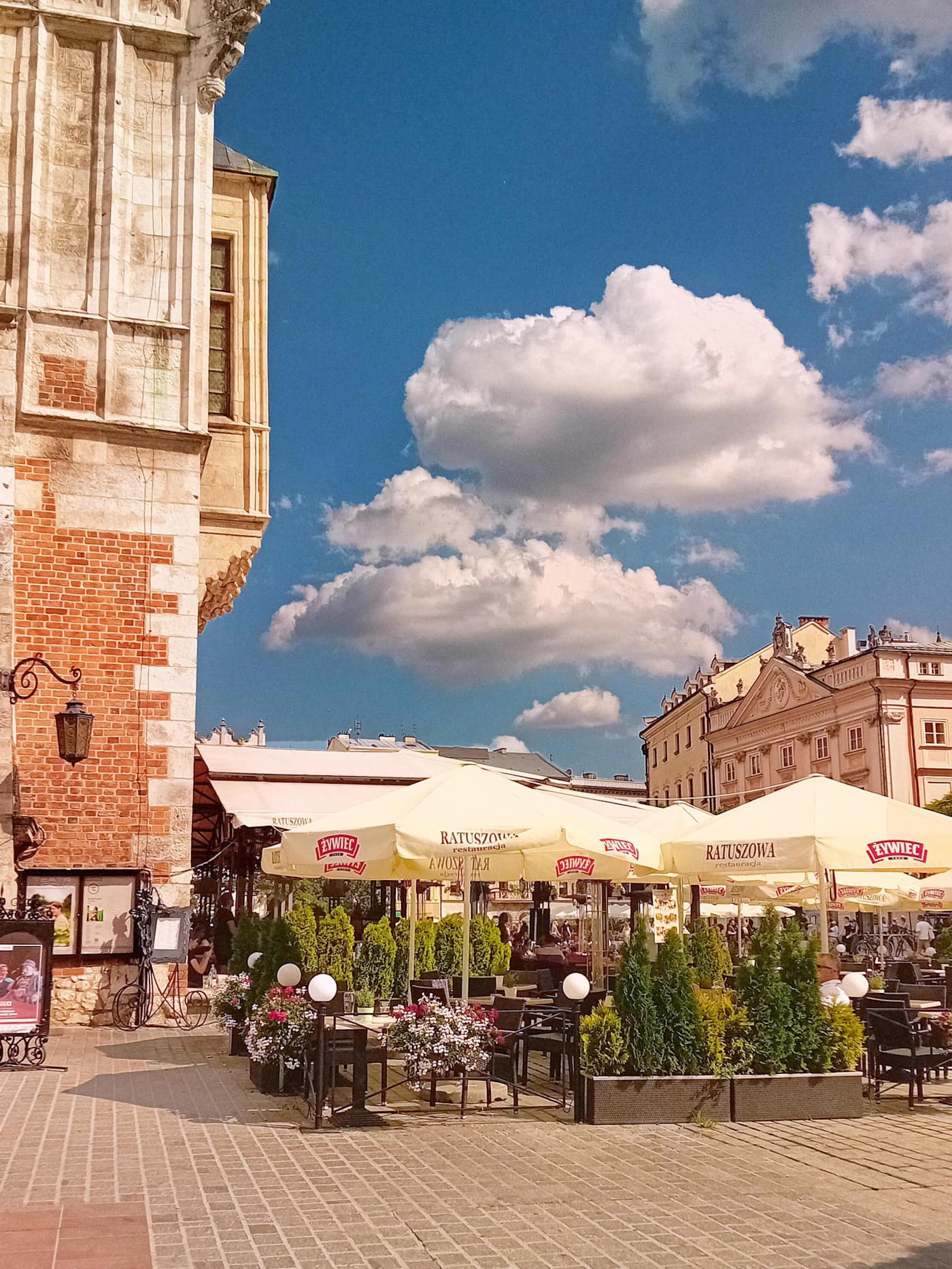 Kraków Old Town square with historic façades, café tables and a dramatic blue sky